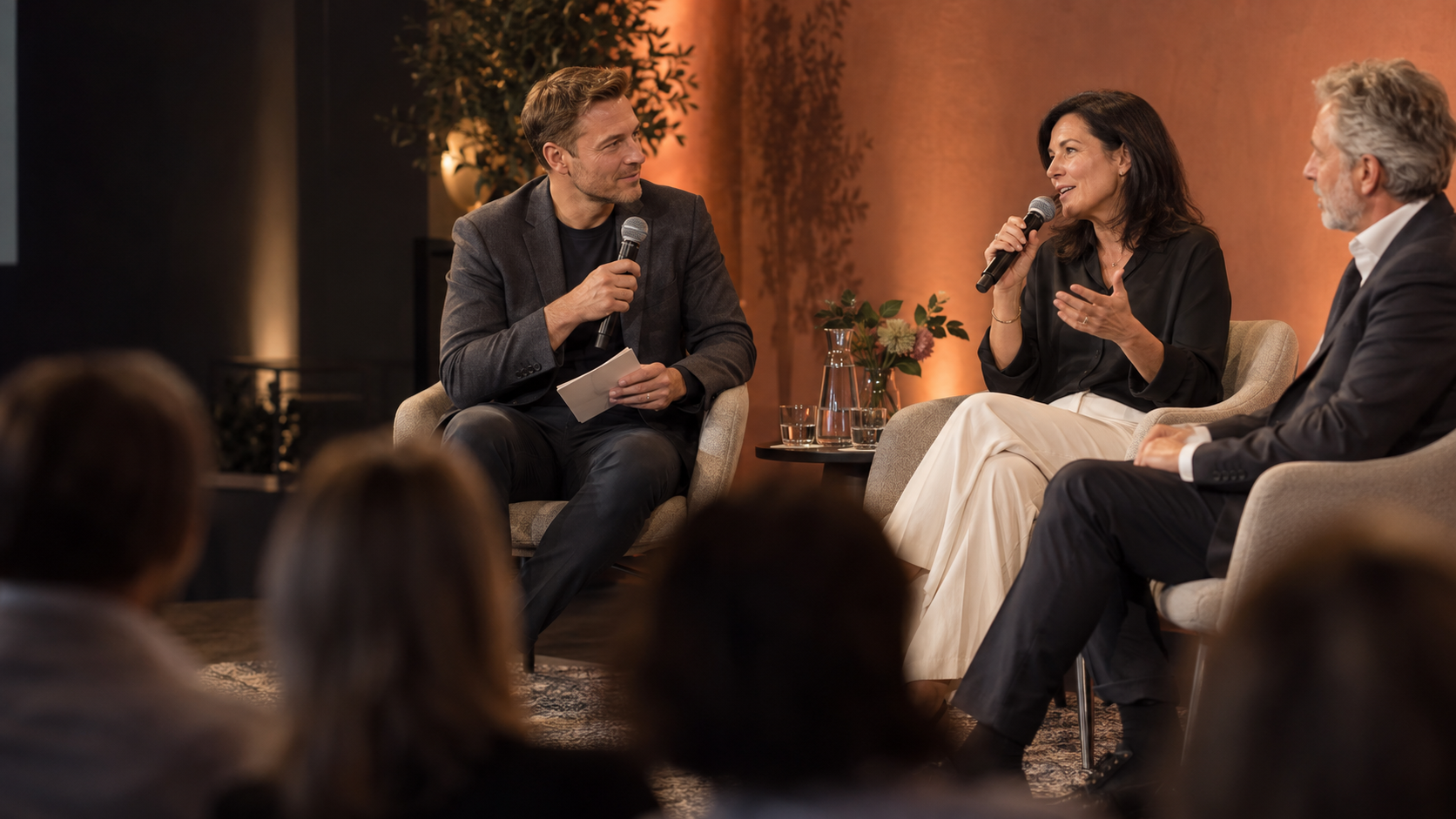 Ein Moderator führt eine Podiumsdiskussion mit zwei Gästen.